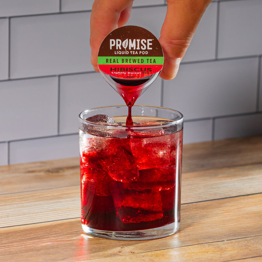 Hand pouring hibiscus tea concentrate over ice