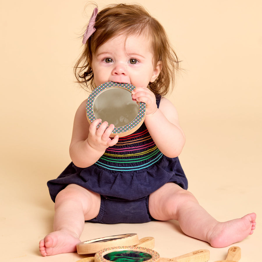 Child holding a round wooden-framed discovery mirror