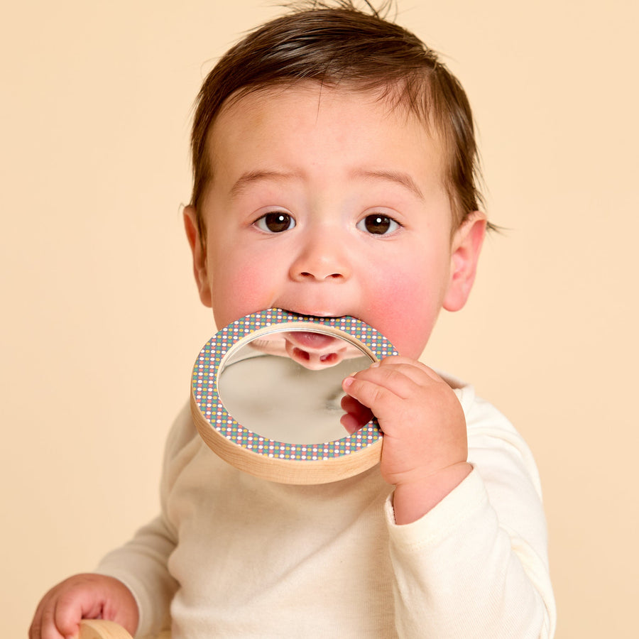 Child holding a round wooden-framed discovery mirror