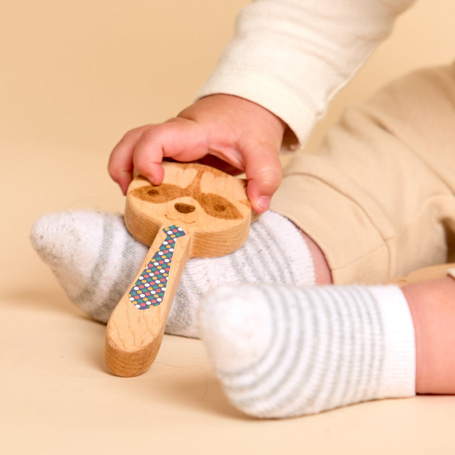 Close-up of a child’s hand holding a printed wooden rattle