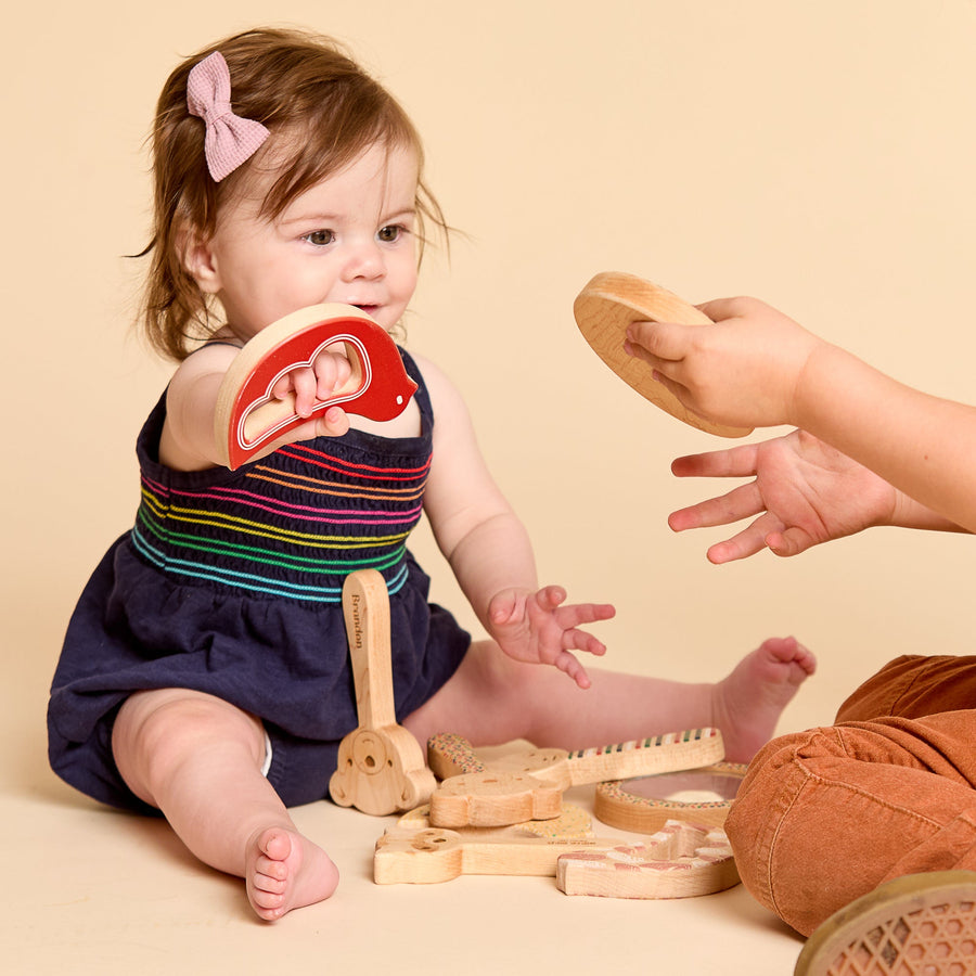 Baby holding a bird-shaped wooden rattle and teether
