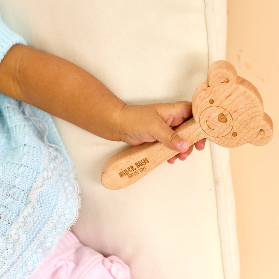 Baby holding a wooden animal-shaped rattle during supervised play