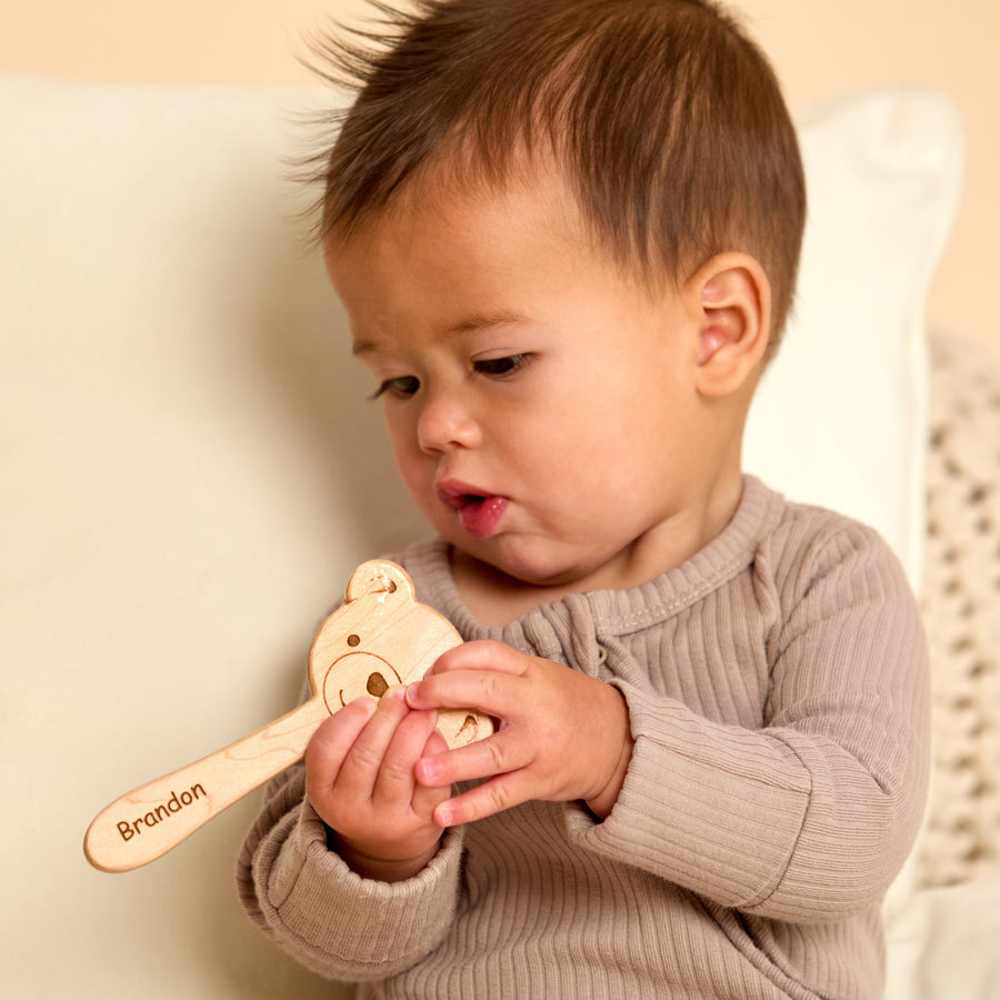 Baby holding a wooden animal-shaped rattle during supervised play