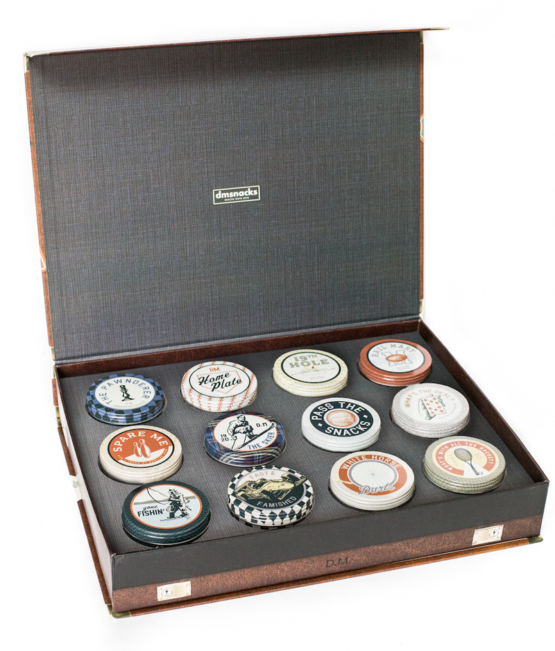 Vintage case of Bar Cart Snacks with a variety of tins containing classic salty snacks perfect for pairing with beverages.