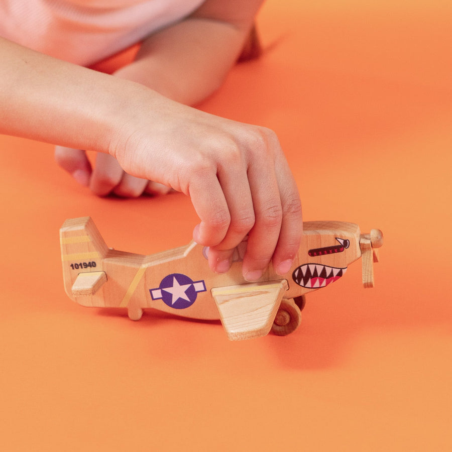 Child’s hands holding and guiding a wooden toy airplane