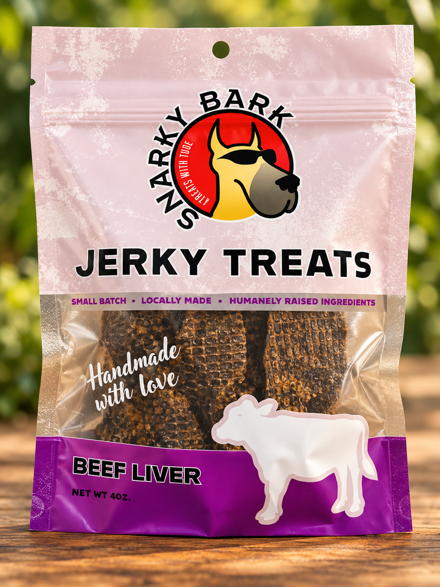 Snarky Bark beef liver jerky in a pink pouch with pieces on a wooden surface