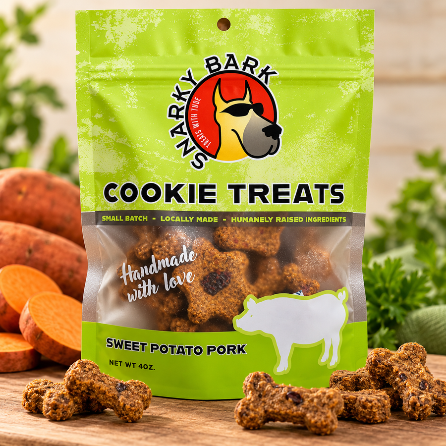 Snarky Bark sweet potato pork cookie treats in a green pouch beside sweet potatoes