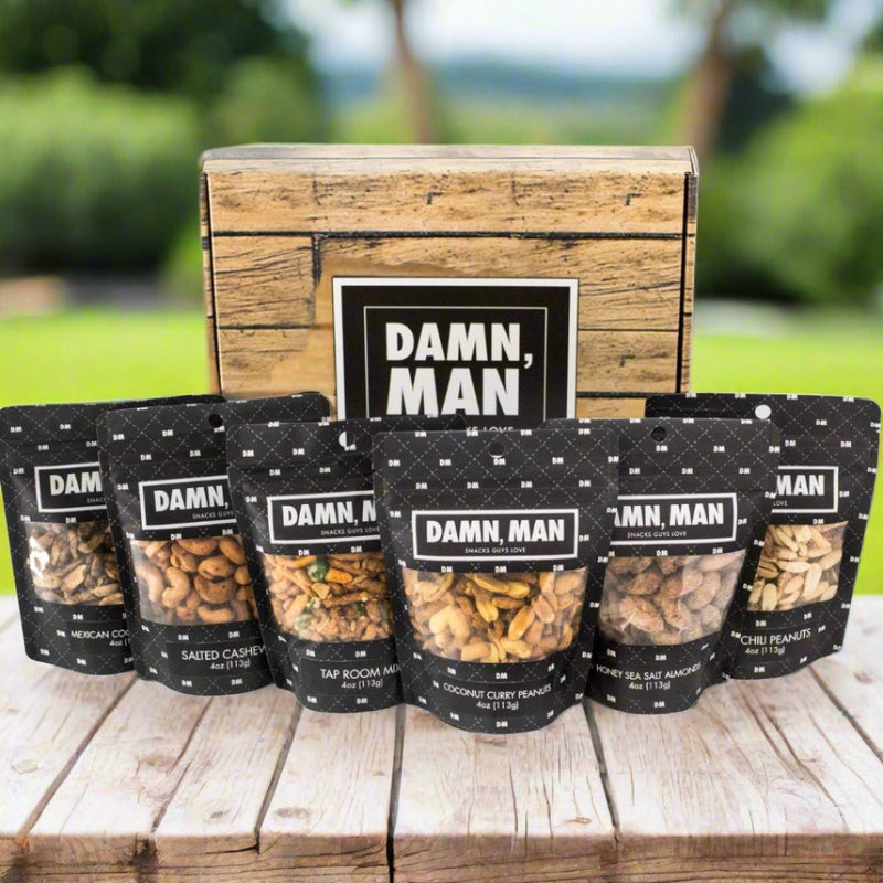 Manly Mixed Nuts Box with assorted nut packs including salted cashews, tap room mix, and honey sea salt almonds displayed on a table
