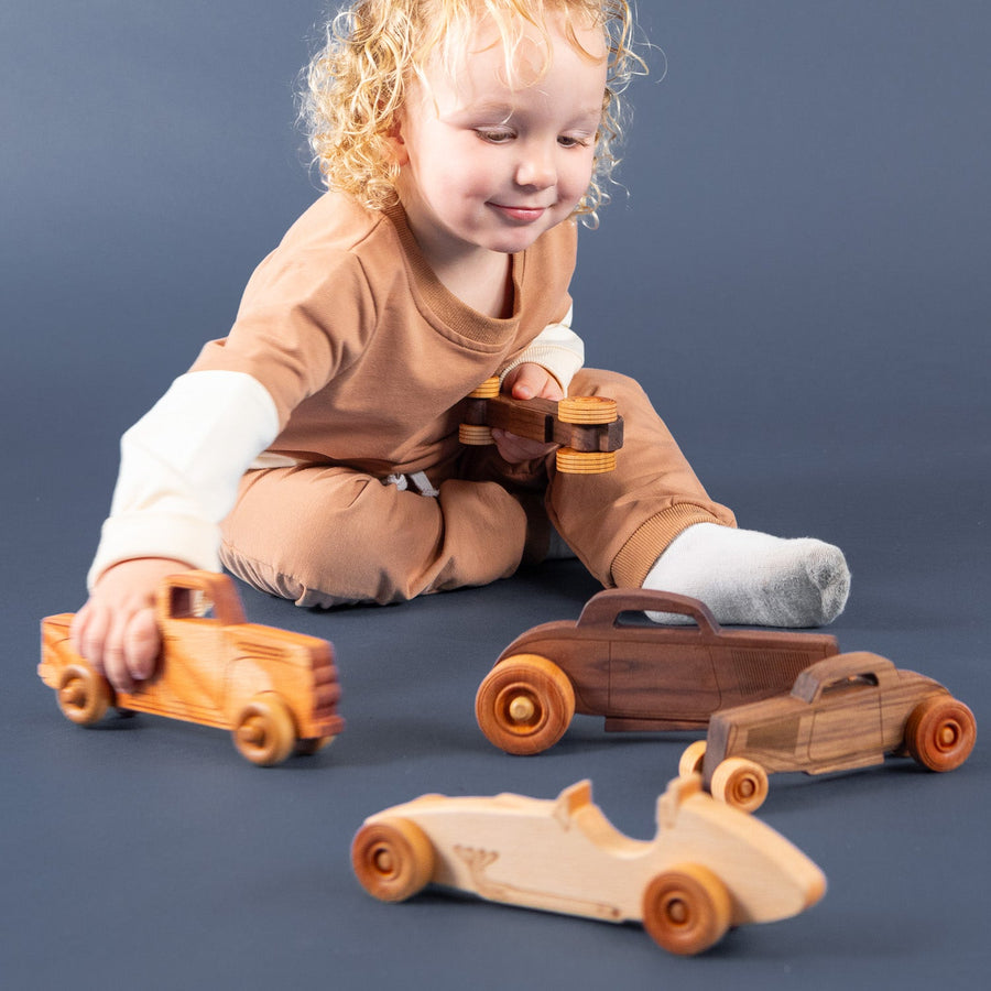 Child playing with a wooden toy car on the floor