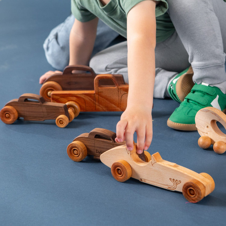 Child sitting on the floor and playing with wooden toy vehicles