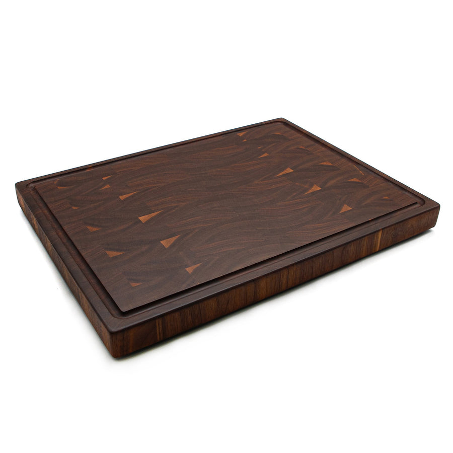 Walnut end-grain cutting board with a perimeter groove, low angled view