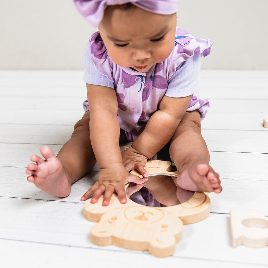Child looking through a bear-shaped wooden discovery mirror