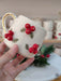A festive handmade ceramic mug adorned with vibrant red berries and green leaf details, featuring a gold handle, perfect for adding holiday cheer to your drinkware collection.