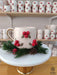 Handmade ceramic mug adorned with bright red berries and festive greenery, displayed on a marble stand with pinecone accents, perfect for holiday cheer.
