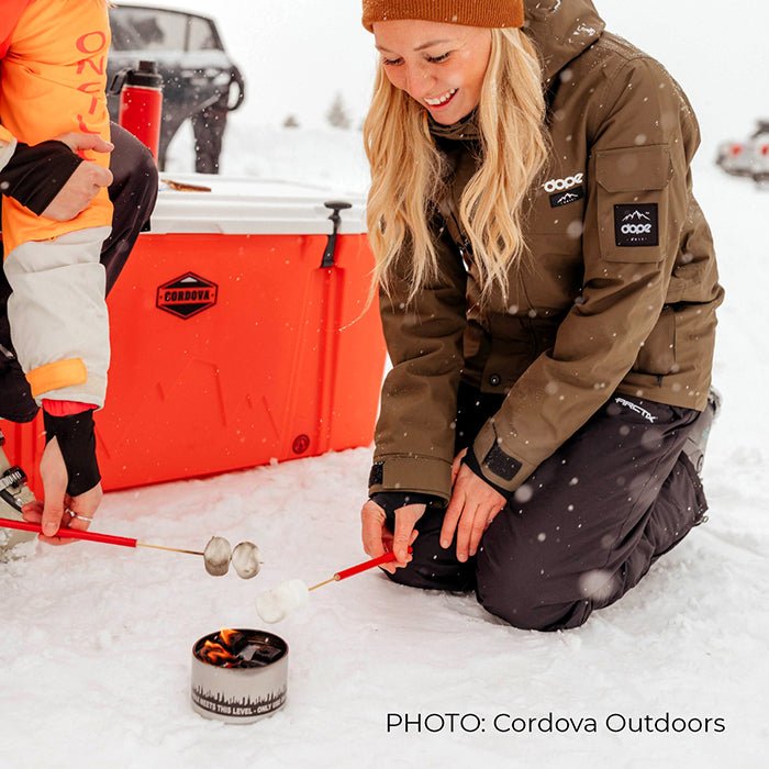 Person using a bonfire beside camping equipment