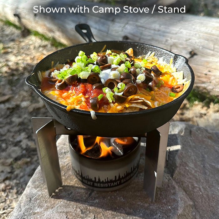 Pan of food supported above a bonfire with a separate stove