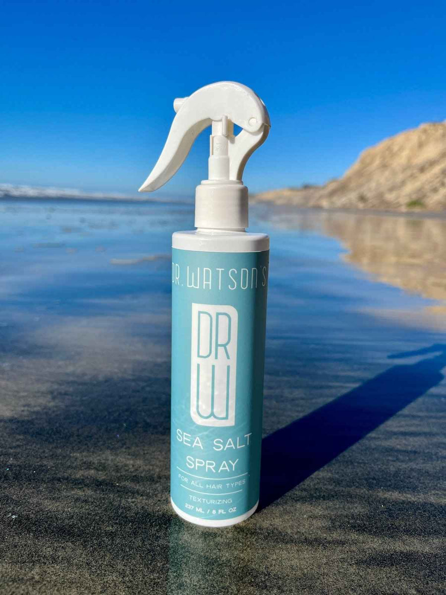 Sea salt spray bottle on a beach with waves behind it