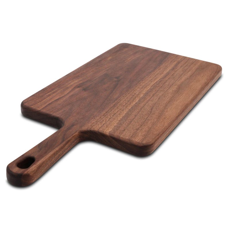 Wide walnut paddle serving board photographed at an angle