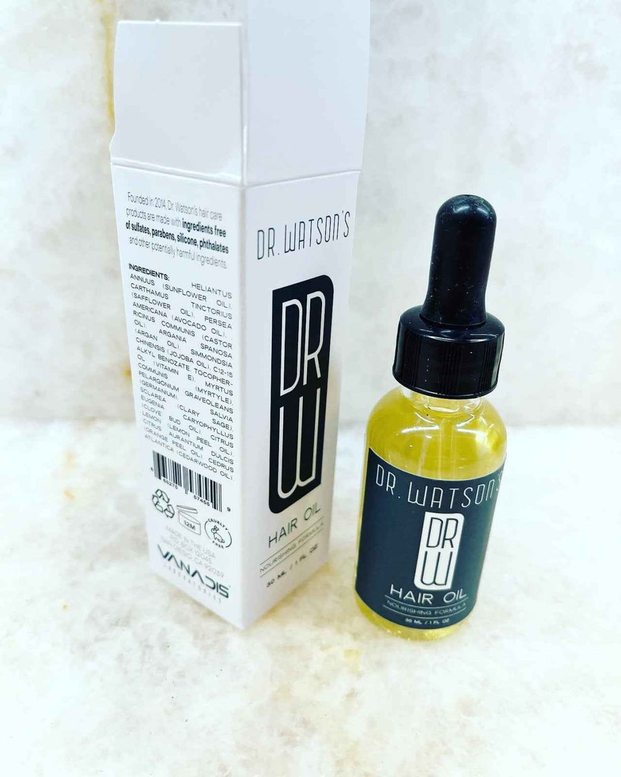 Hair oil bottle beside the ingredient panel on its carton