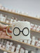 Handmade ceramic mug inspired by a beloved wizard, featuring iconic round glasses and a lightning bolt in delicate gold. The subtle, minimalist design brings a touch of magic to every sip.