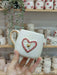 A handmade ceramic mug featuring a 3D heart design with a gold heart centerpiece, surrounded by a red floral frame, and a gold handle, perfect for gifts.
