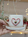 Hand holding a ceramic espresso cup with a 3D red and gold heart design, paired with a matching saucer, ideal for Valentine's Day or romantic occasions.