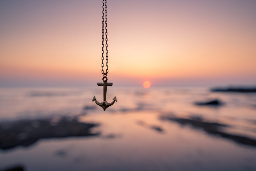 Anchor pendant hanging in front of a sunset shoreline