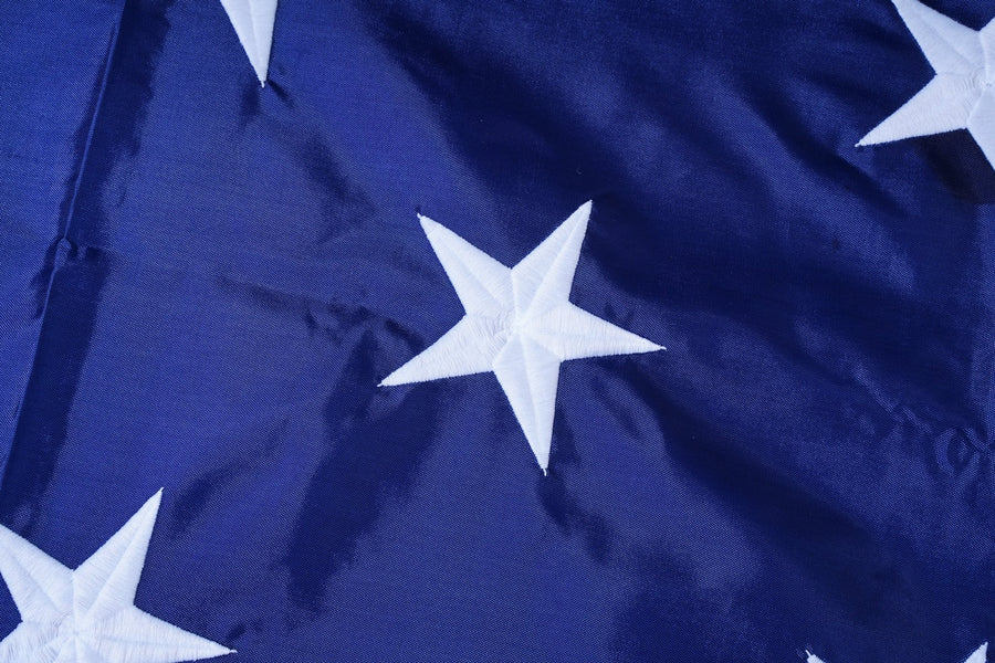 Close-up of embroidered white stars on blue flag fabric