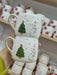 A pair of handmade ceramic mugs featuring a festive holiday design with a snowman and a Christmas tree, adorned with golden accents on the handles. Perfect for bringing a touch of warmth and cheer to your holiday gatherings or gifting to loved ones during the season.