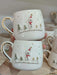 Handmade ceramic mugs showcasing a delightful snowman in a cozy winter village scene, surrounded by snowy trees and golden-roofed houses. The gold-accented handle adds a touch of elegance, perfect for enjoying warm drinks during the festive season.