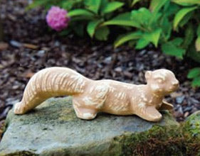 Stoneware squirrel figurine resting on an outdoor stone