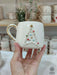 A handmade Star Trek-inspired ceramic Christmas mug featuring a 3D Christmas tree with colorful baubles, a gold star, and a gold handle, perfect for Trekkie fans.