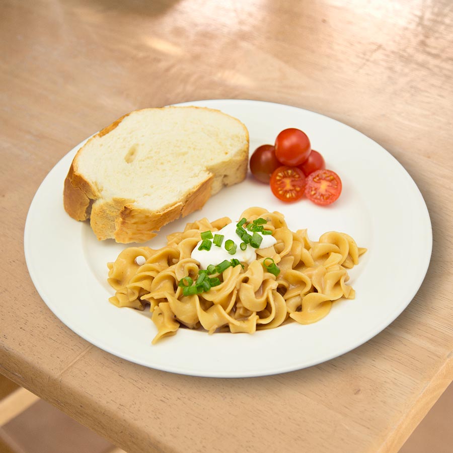 Prepared stroganoff with bread and tomatoes, serving suggestion
