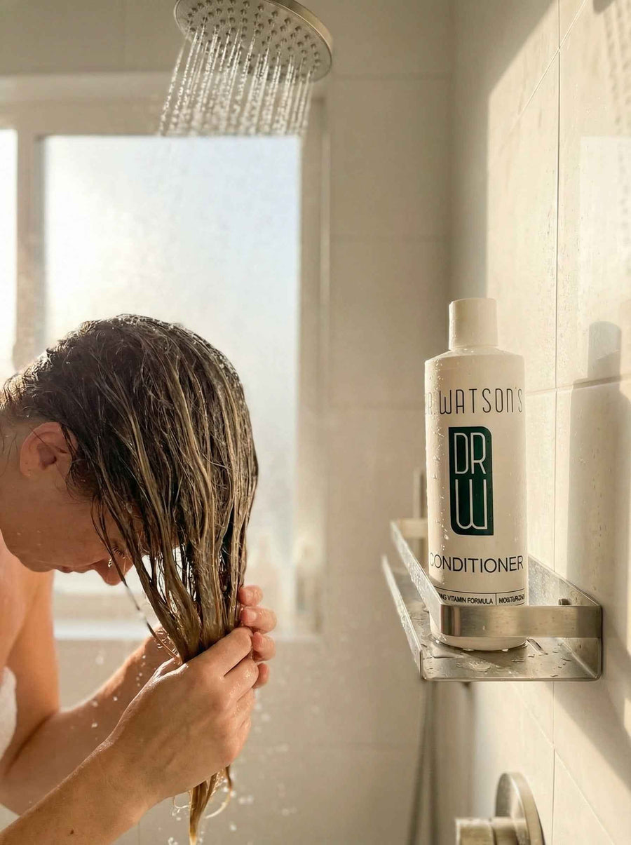 Person applying conditioner to wet hair beside a conditioner bottle
